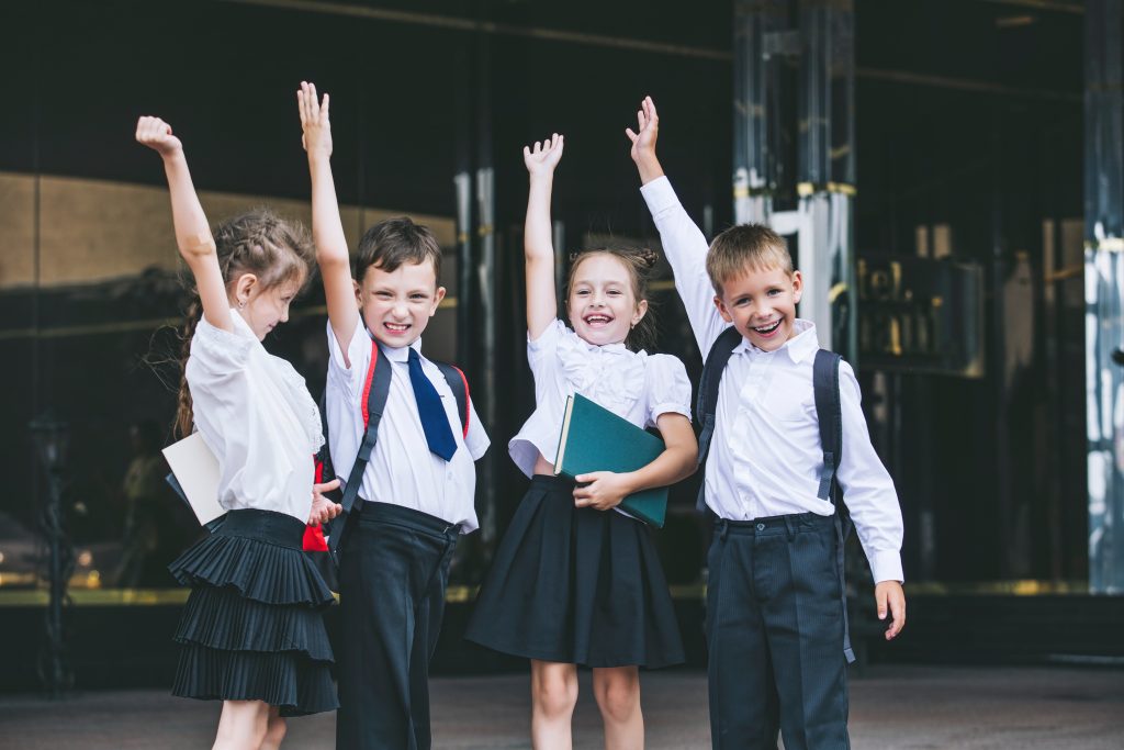 Beautiful school children active and happy on the background of school in uniform