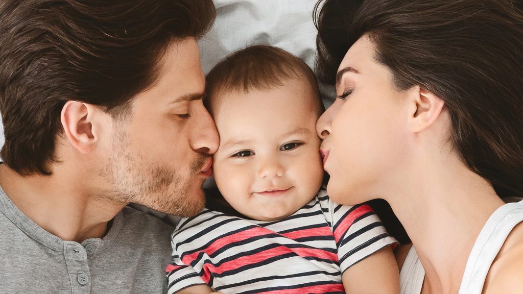 Beloved baby. Parents kissing their cute infant, closeup, panorama