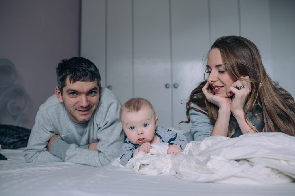 Portrait of happy young family playing on bed in the bedroom