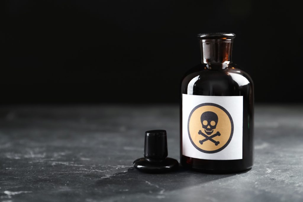 Open glass bottle of poison with warning sign on black table. Space for text